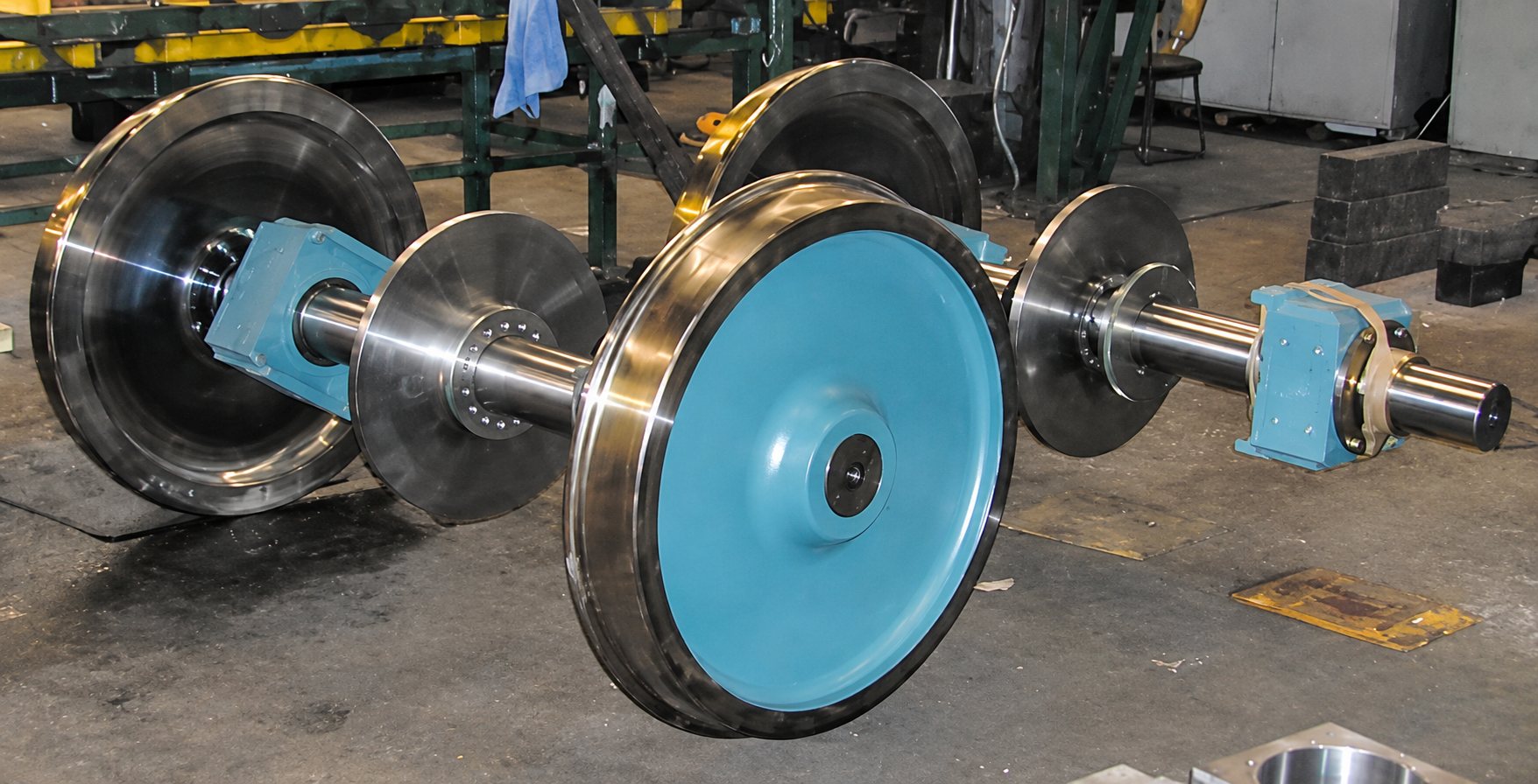 Essieux ferroviaires avec roues bleues posés dans un atelier industriel
