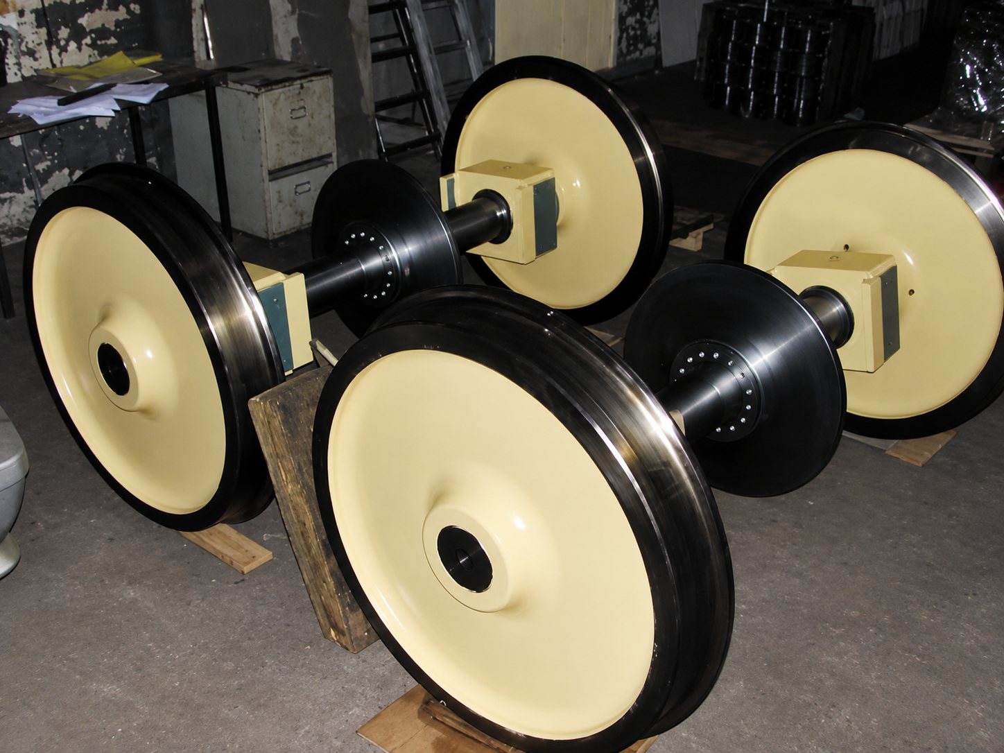 Essieux ferroviaires avec grandes roues crème posés dans un atelier