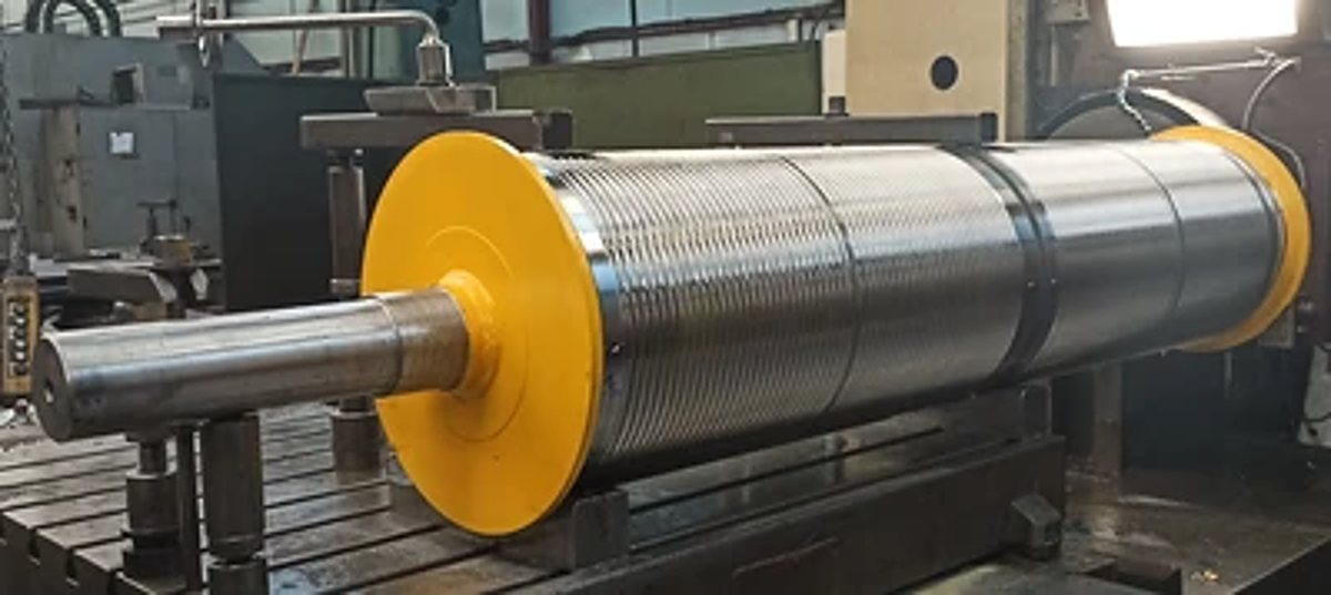 Gros rouleau industriel en acier avec disques jaunes dans un atelier